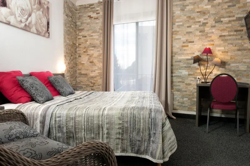Une chambre avec un lit recouvert d'une courtepointe et un bureau rouge.