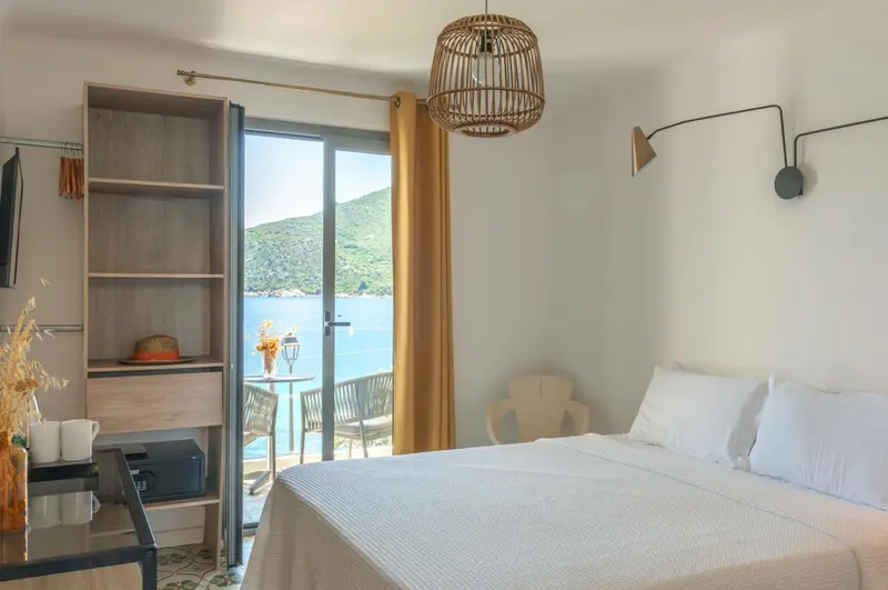 Chambre lumineuse avec un lit blanc et une vue sur la mer.