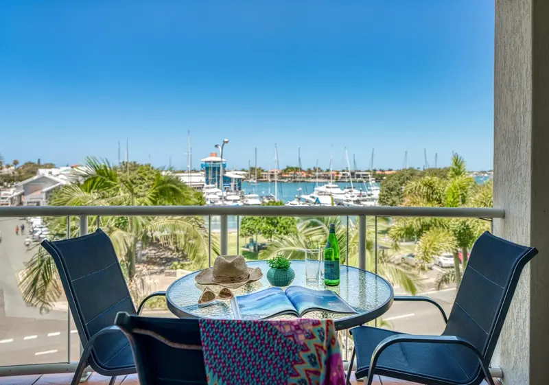 Vue d'une terrasse avec mobilier et vue sur un port de plaisance.