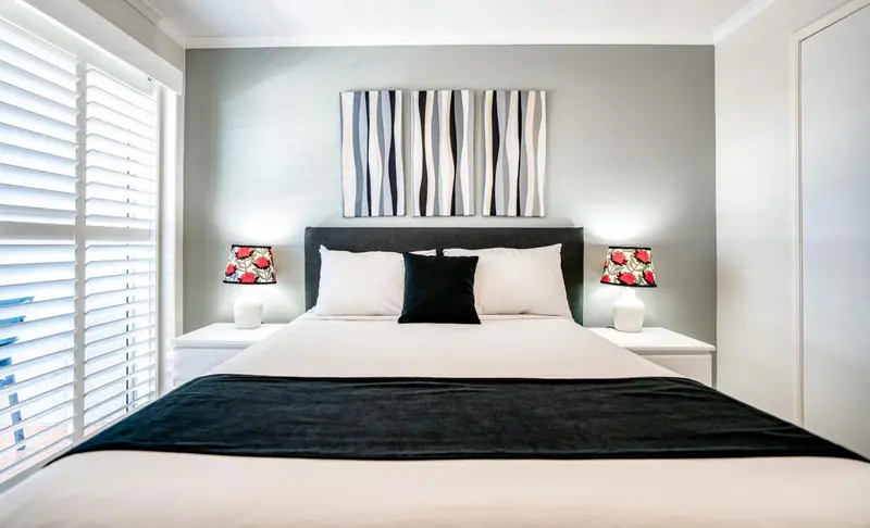 Une chambre moderne avec un grand lit recouvert d'une courtepointe blanche et noire.