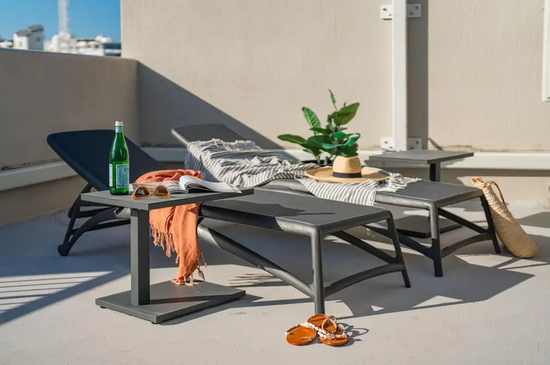 Transats et table d'appoint sur une terrasse ensoleillée.