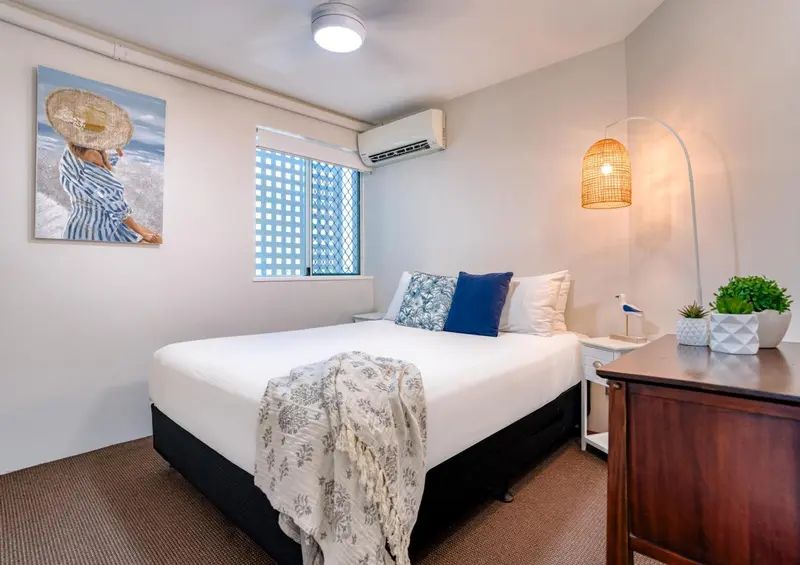 Une chambre lumineuse avec un lit recouvert d'une couverture et de coussins.