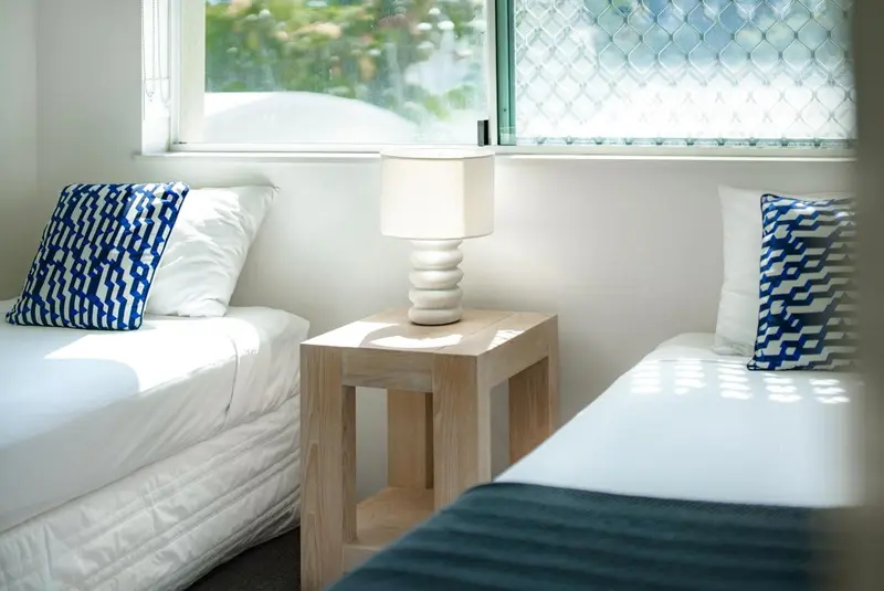 Une chambre lumineuse avec deux lits simples et des oreillers décorés.