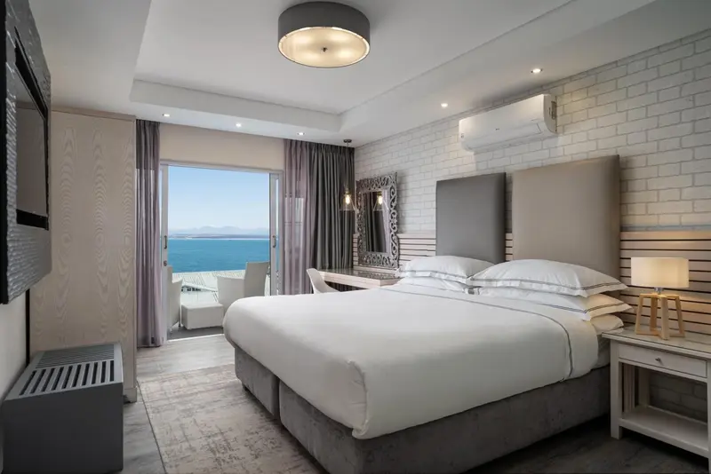 Une chambre lumineuse avec un grand lit face à la mer.