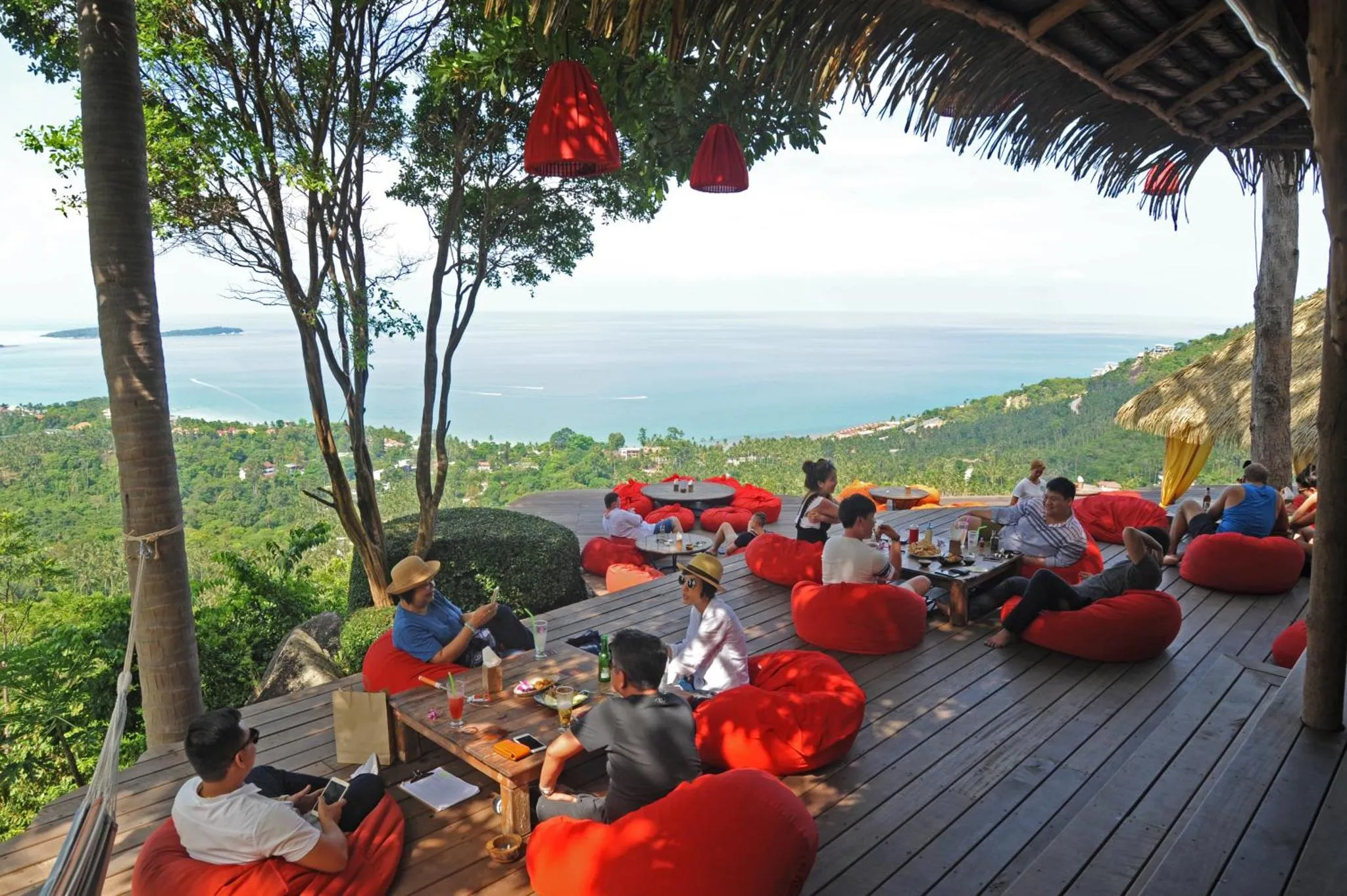 Des clients se détendent sur des fauteuils colorés avec vue sur la mer.