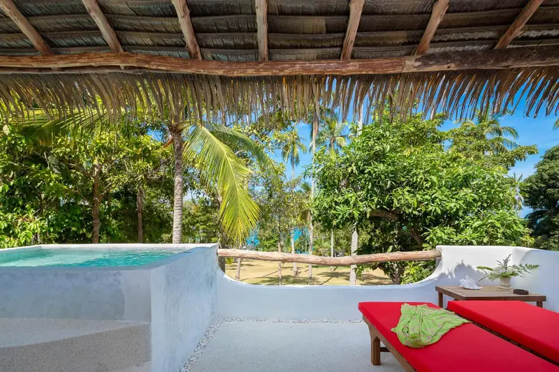 Terrasse avec jacuzzi et mobilier de détente face à la végétation tropicale.