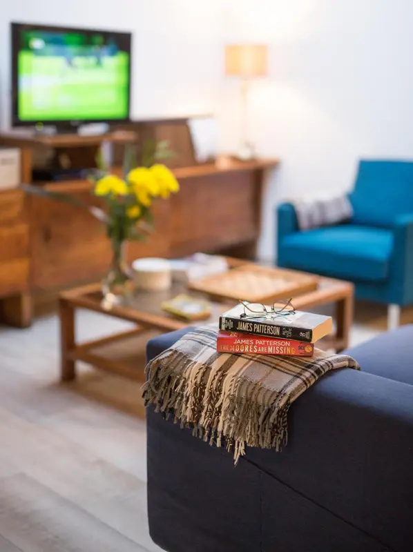 Un salon lumineux avec un canapé bleu foncé et une table basse en bois.