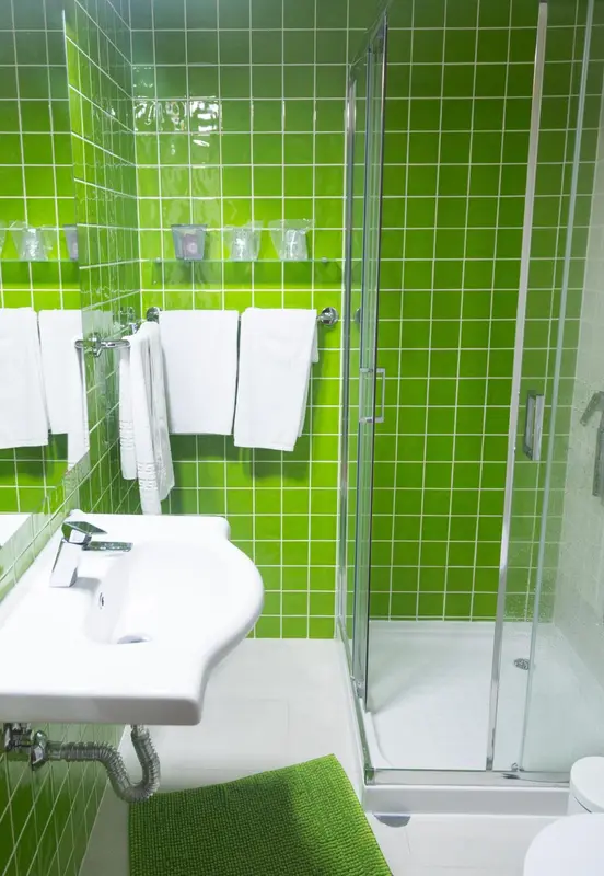 Une salle de bain moderne avec des carreaux verts et une douche vitree.
