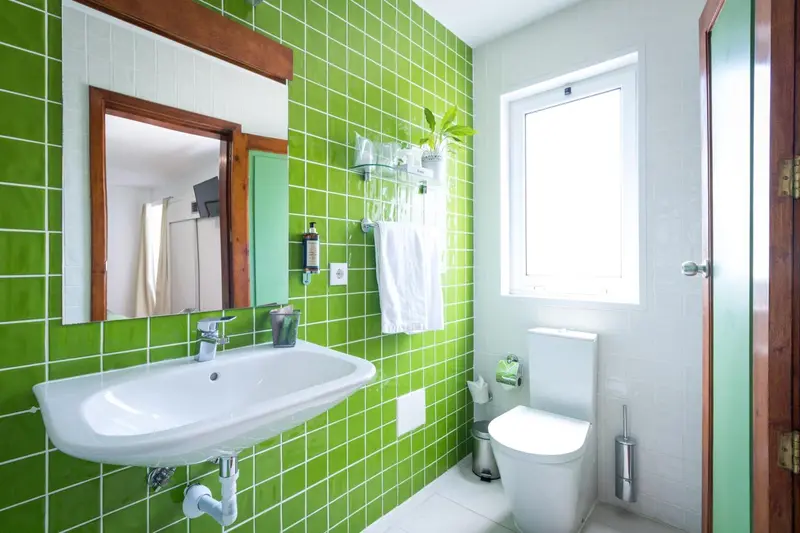Une salle de bain lumineuse avec des murs carrelés de vert et blanc.