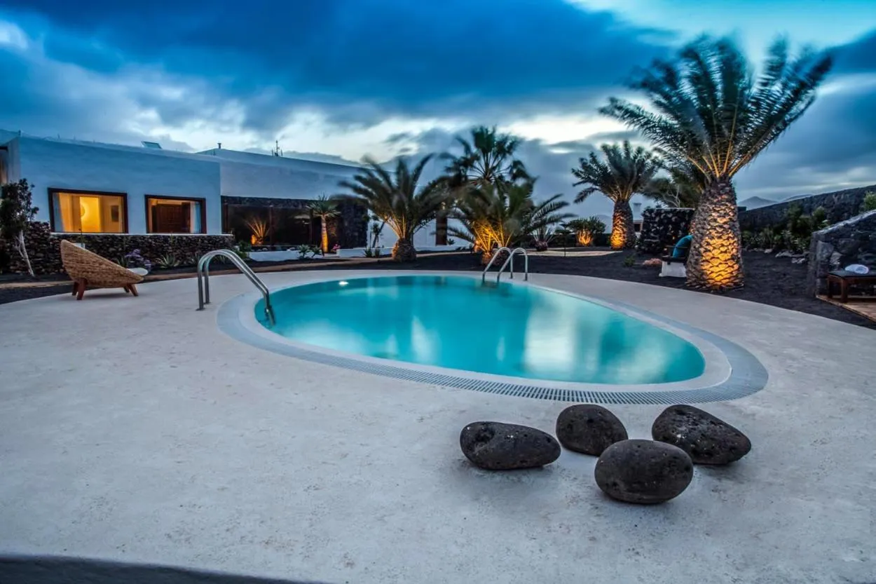 Piscine extérieure éclairée au crépuscule avec végétation tropicale.