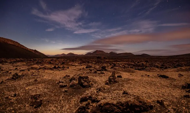 Paysage nocturne de montagnes volcaniques sous un ciel étoilé.