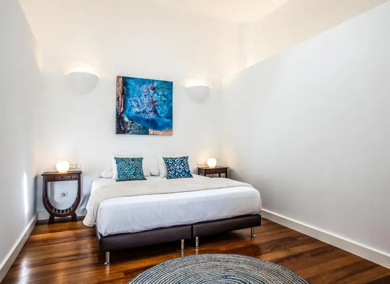 Une chambre lumineuse avec un grand lit recouvert d'une courtepointe blanche.