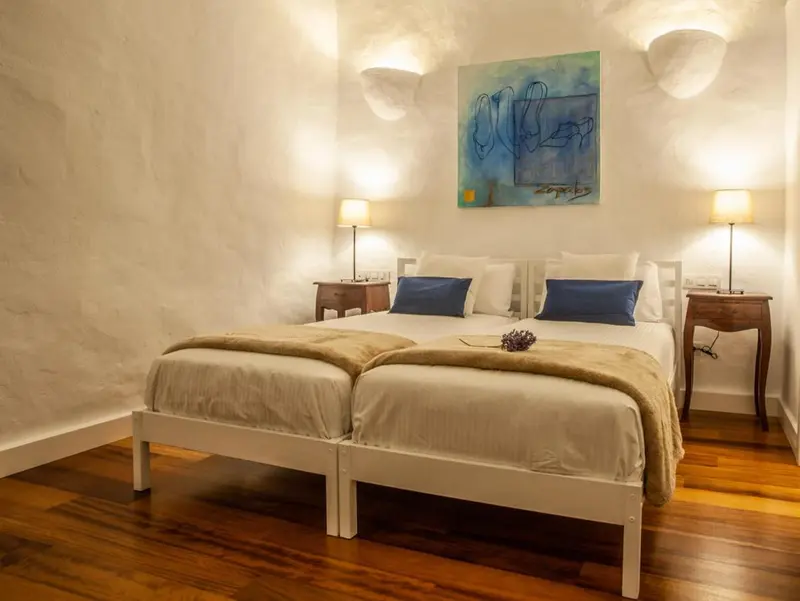 Une chambre lumineuse avec deux lits simples et une décoration murale abstraite.
