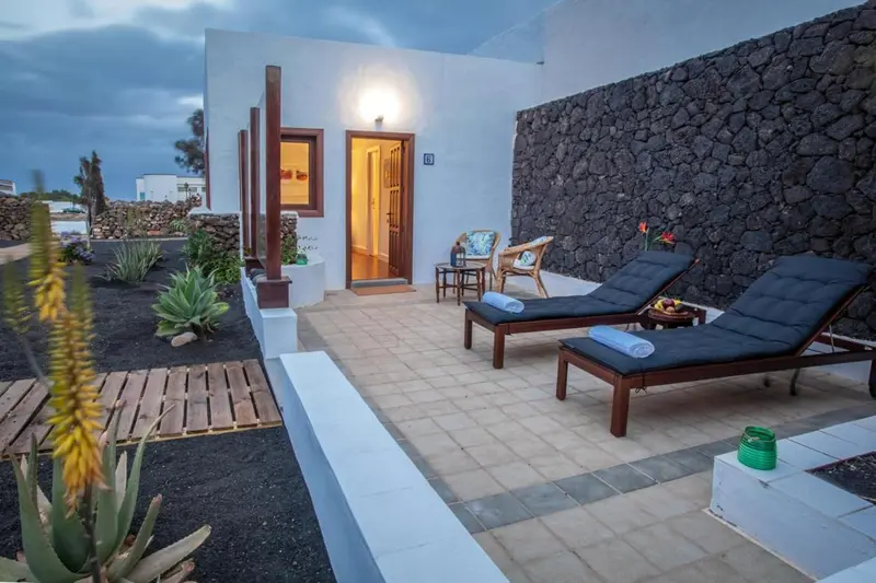 Terrasse privative avec mobilier de jardin devant une entrée.
