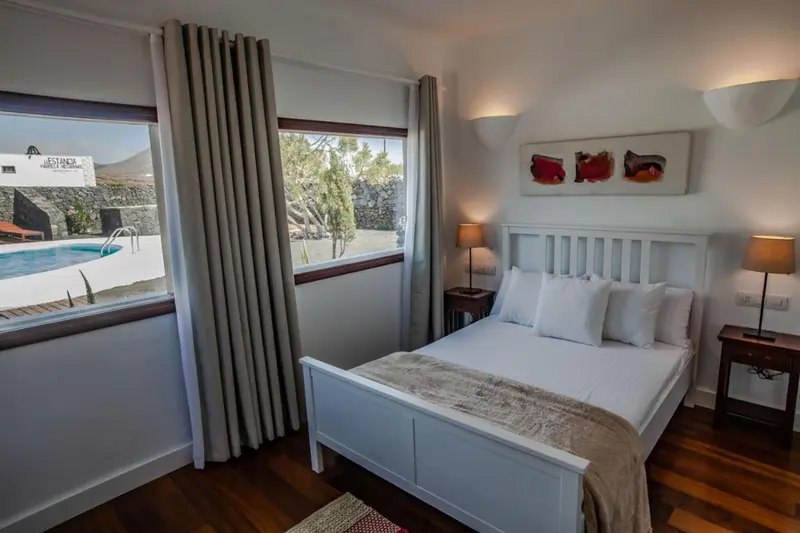 Une chambre lumineuse avec un lit double et un rideau beige.