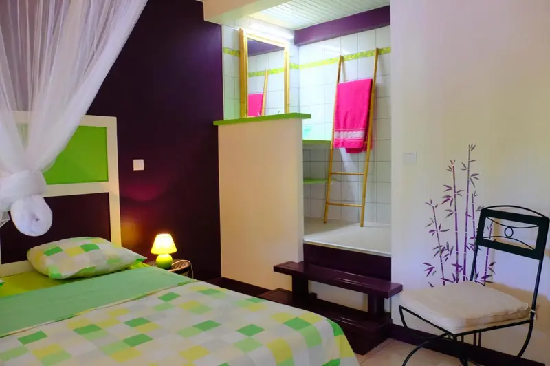 Une chambre lumineuse avec un lit et une salle de bain ouverte.