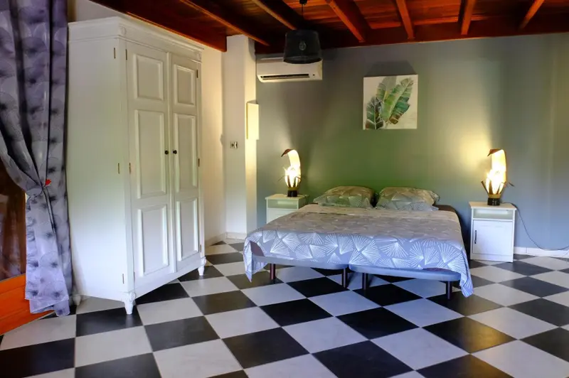 Une chambre avec un grand lit et un sol carrelé noir et blanc.