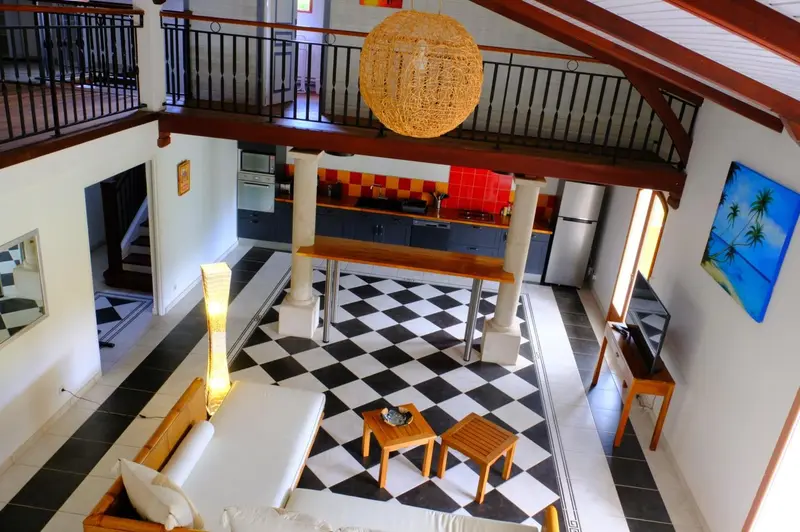 Espace de vie intérieur lumineux avec cuisine ouverte et sol à carreaux.