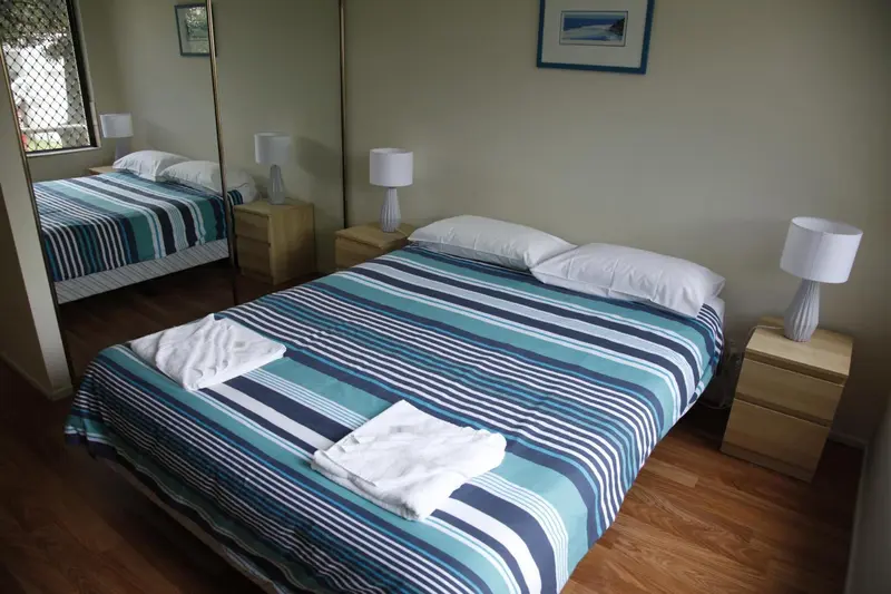 Une chambre lumineuse avec un lit recouvert d'une couette à rayures et des tables de chevet.