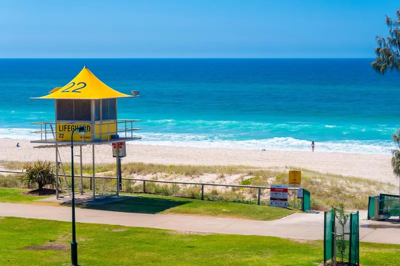 Une plage de sable fin bordée d'une eau turquoise sous un ciel bleu.