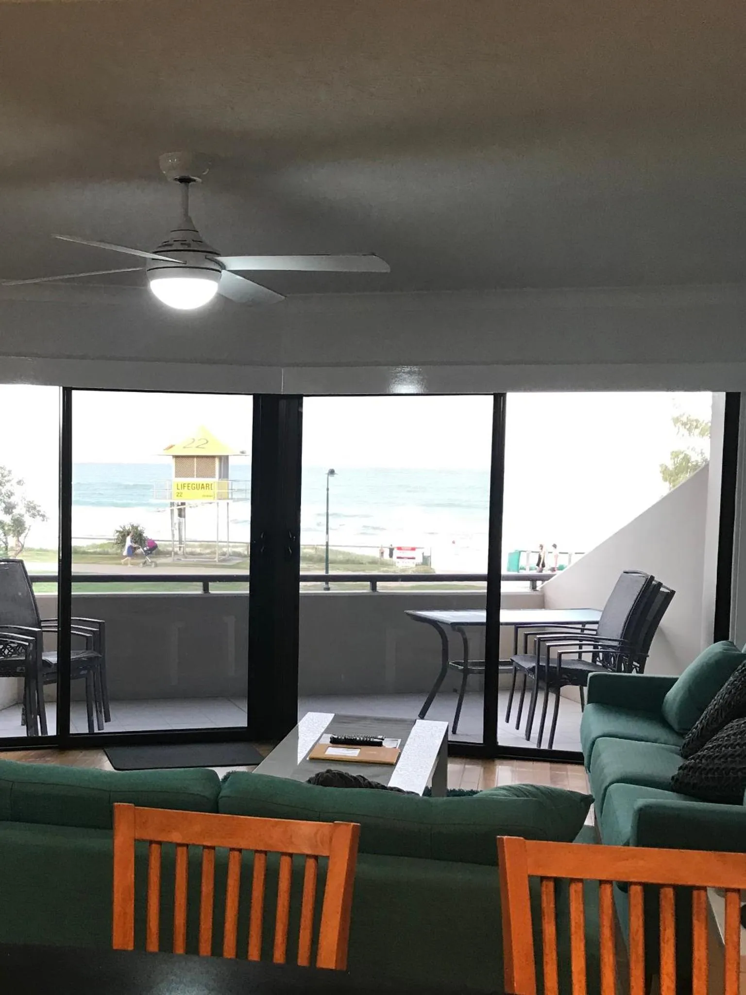 Espace de détente intérieur avec canapés verts et vue sur la mer.