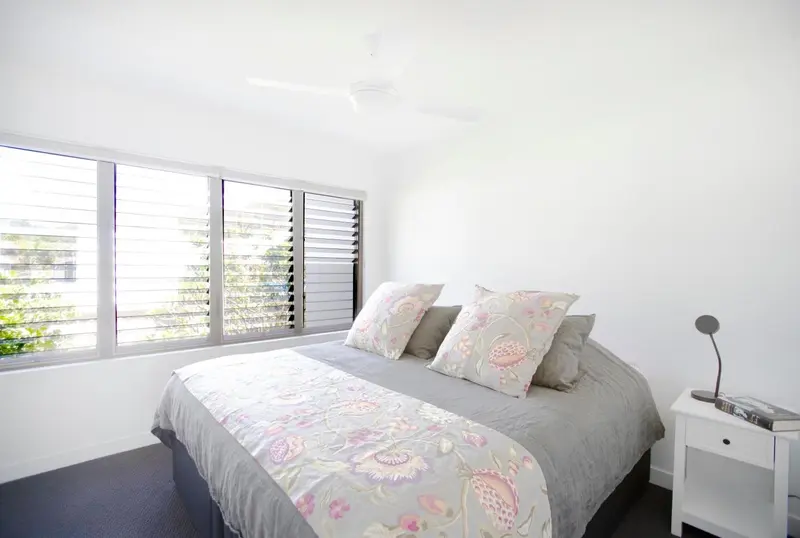 Une chambre lumineuse avec un grand lit recouvert d'une couette à motifs floraux.