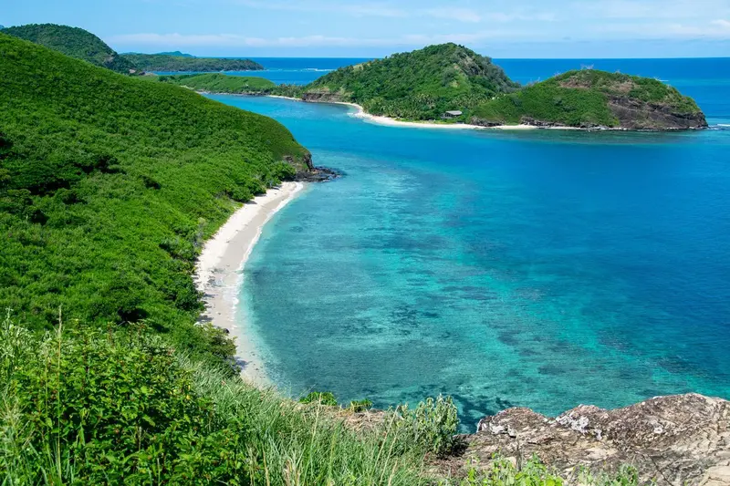 Vue aérienne d'une côte tropicale avec une plage de sable blanc et une eau turquoise.