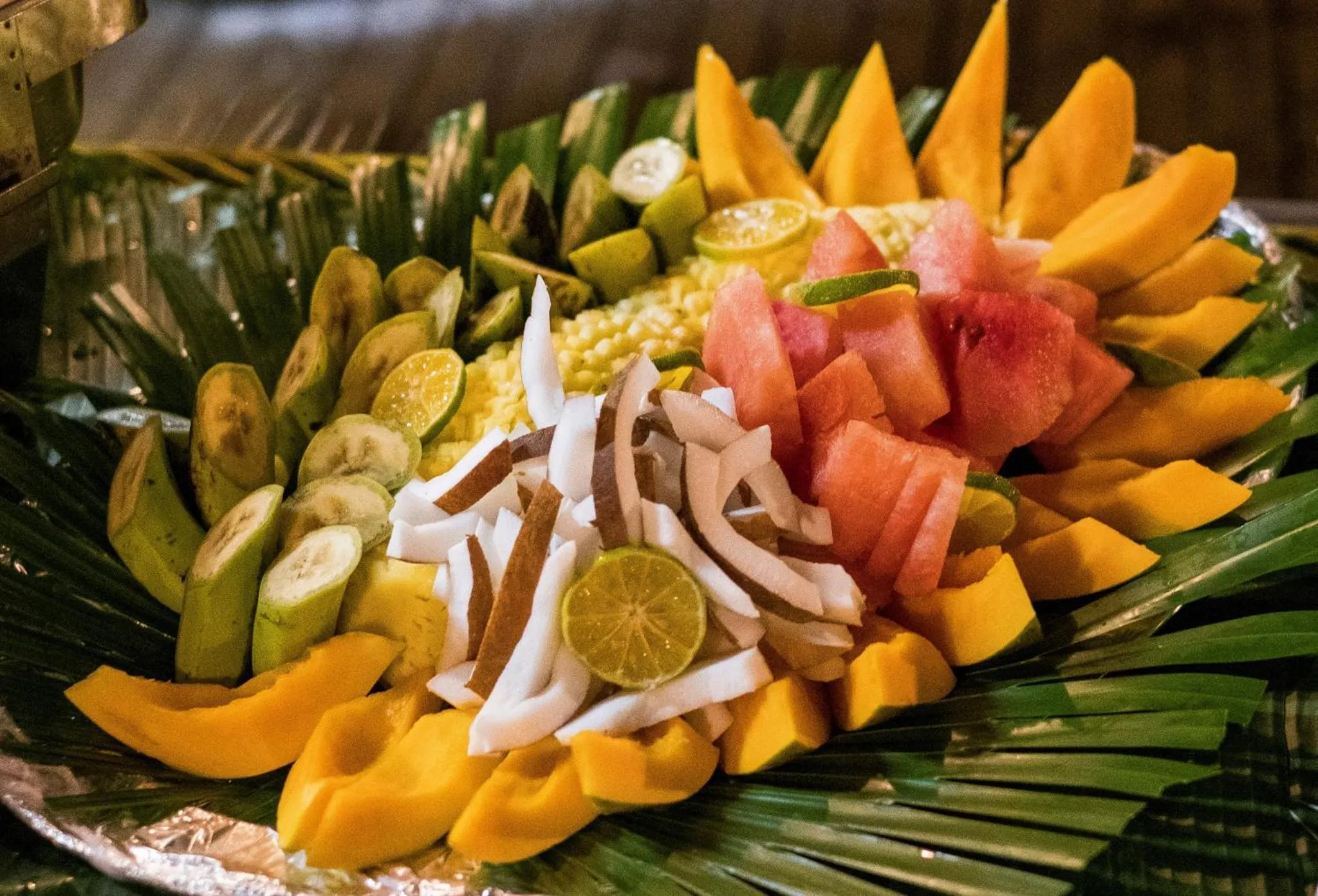 Assortiment de fruits frais disposés sur un plat décoré de feuilles de palmier.