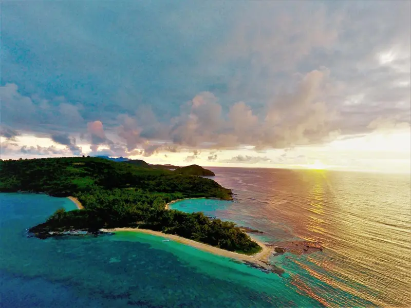 Vue aérienne d'une côte tropicale avec des plages et une végétation luxuriante.