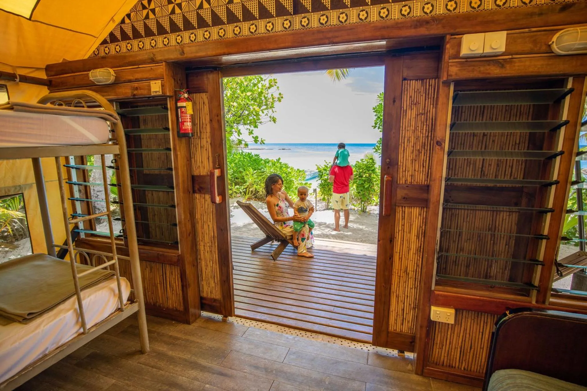 Une femme et un enfant sont assis sur une terrasse en bois avec vue sur la mer.