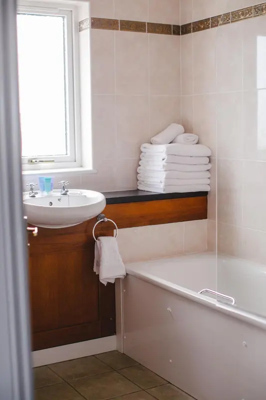 Une salle de bain avec baignoire, lavabo et serviettes pliées.