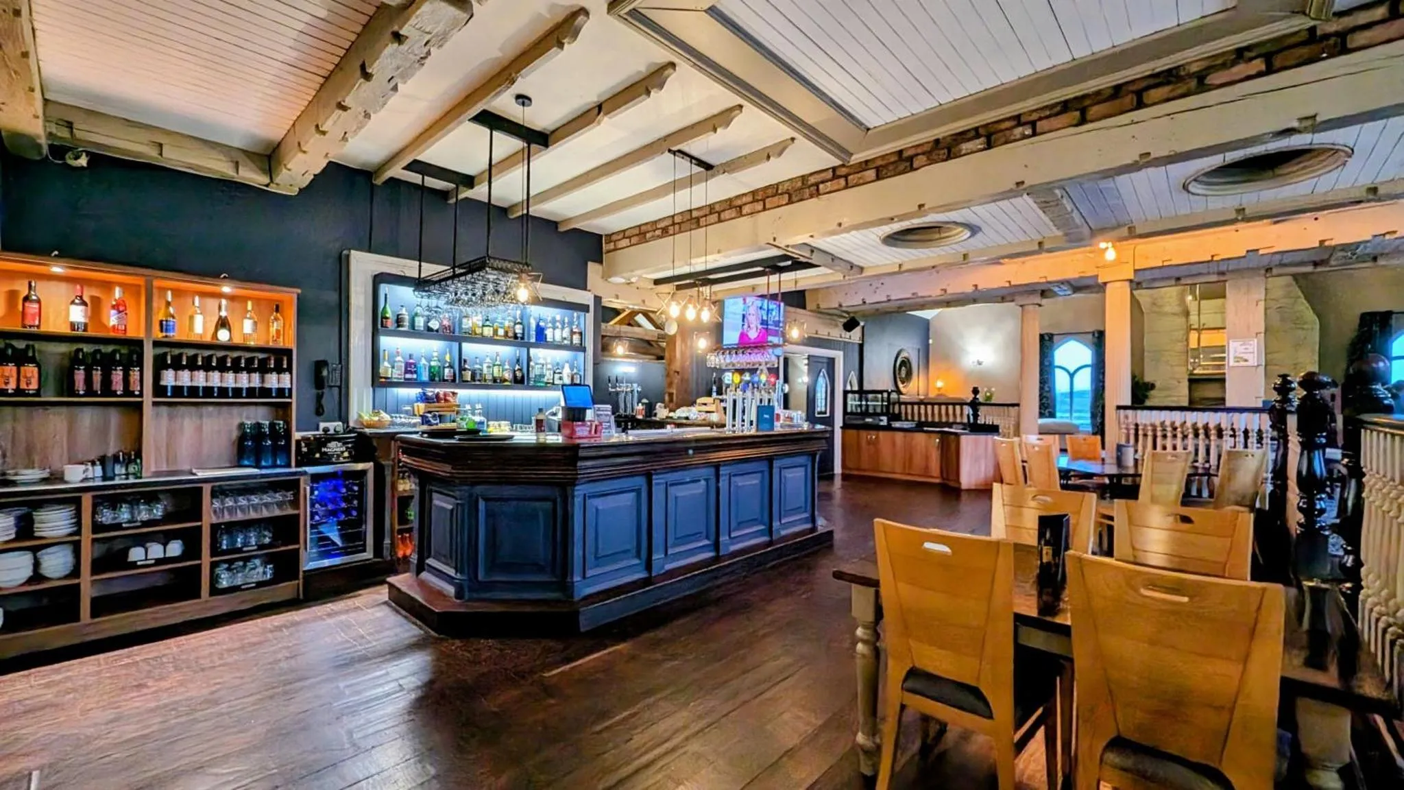 Un bar spacieux avec un comptoir bien garni et des tables en bois.