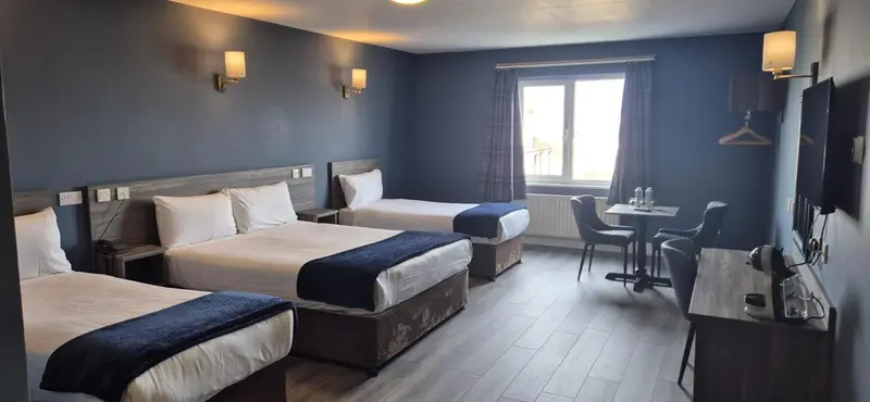 Chambre avec deux lits simples et un coin repas près de la fenêtre.