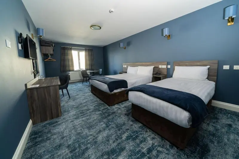 Une chambre d'hôtel avec deux lits simples et un bureau.