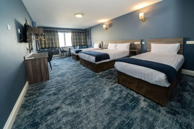 Chambre d'hôtel avec deux lits doubles et un bureau.