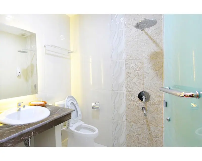 Une salle de bain claire avec douche à l'italienne et lavabo.