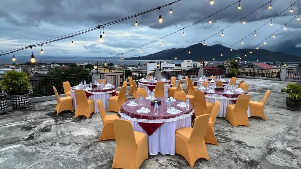 Terrasse aménagée avec tables et chaises pour un repas en extérieur, vue sur la ville et les montagnes.