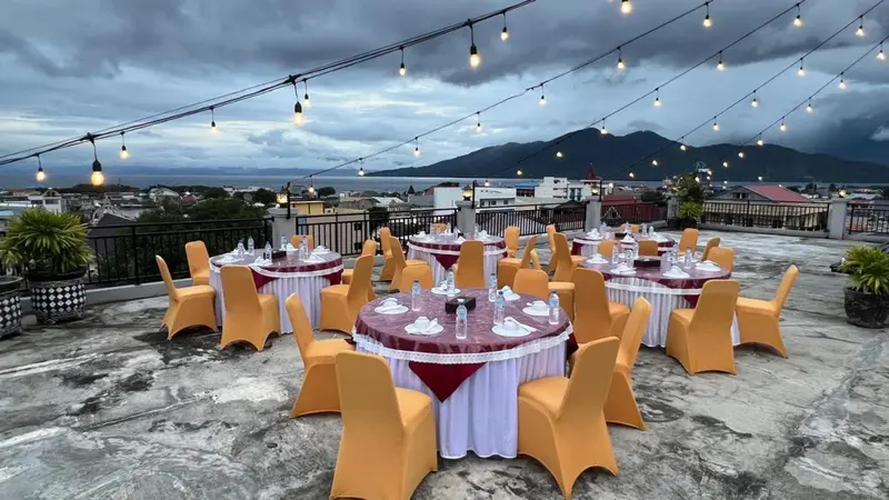 Terrasse aménagée avec tables et chaises pour un repas en extérieur, vue sur la ville et les montagnes.