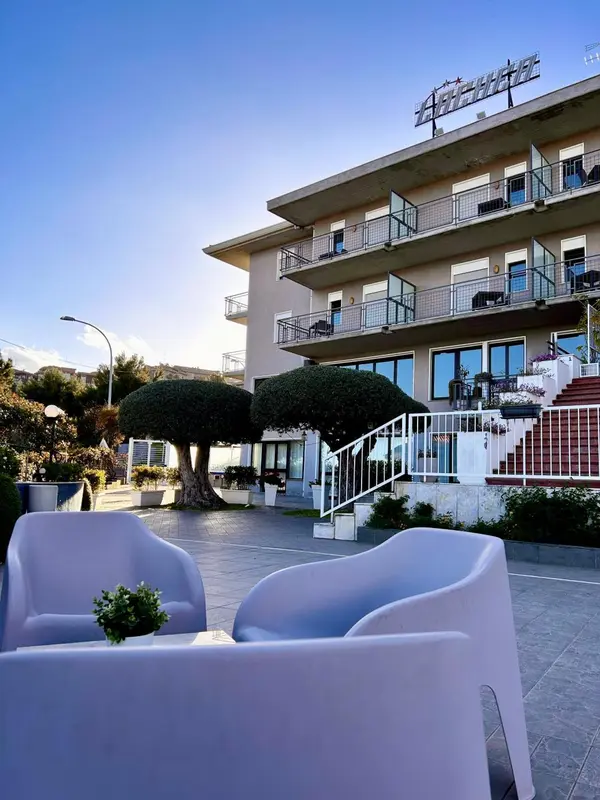 Façade d'un bâtiment blanc avec des balcons et des espaces extérieurs aménagés.