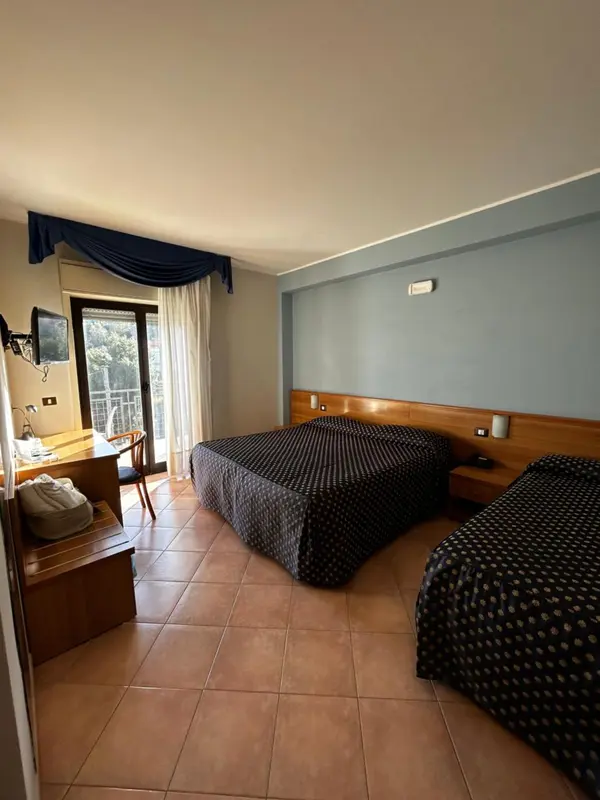 Chambre avec deux lits et bureau près d'une fenêtre.