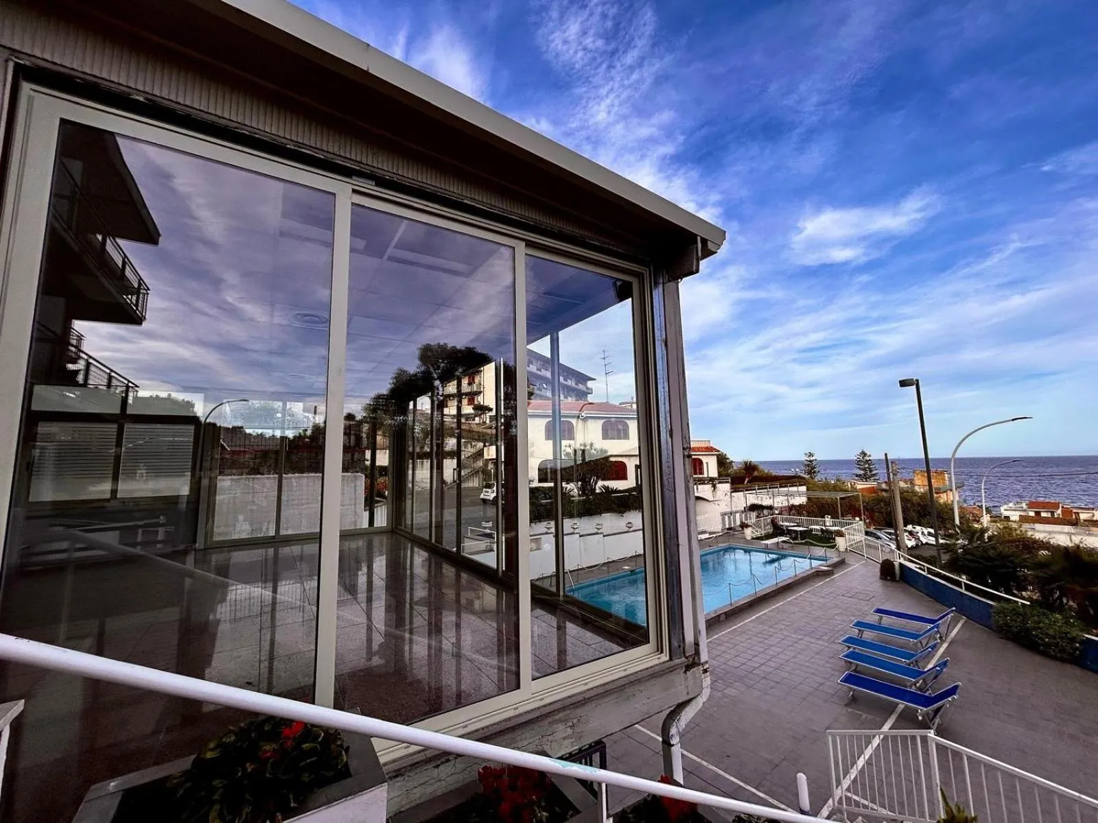 Terrasse vitrée donnant sur une piscine et la mer.