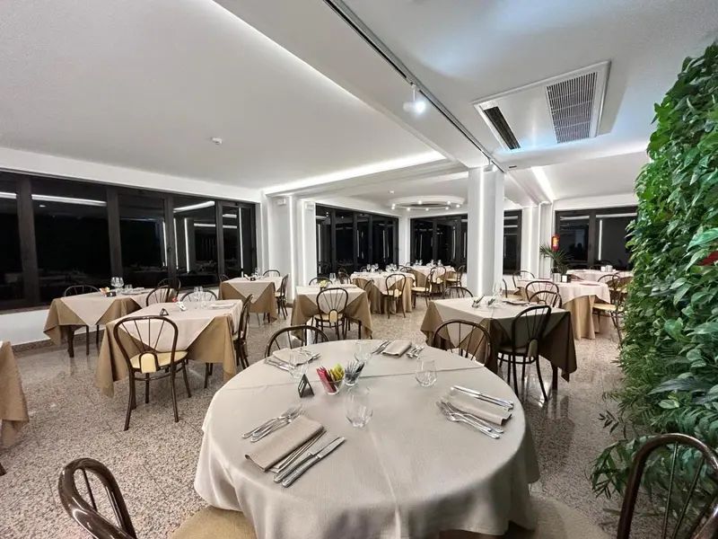 Une salle lumineuse avec des tables dressées pour un repas.