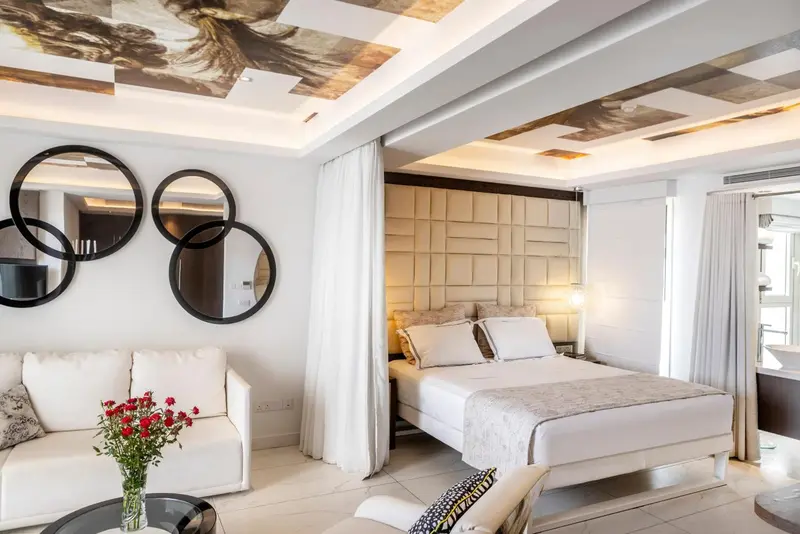 Une chambre lumineuse avec un canapé blanc et un grand lit.