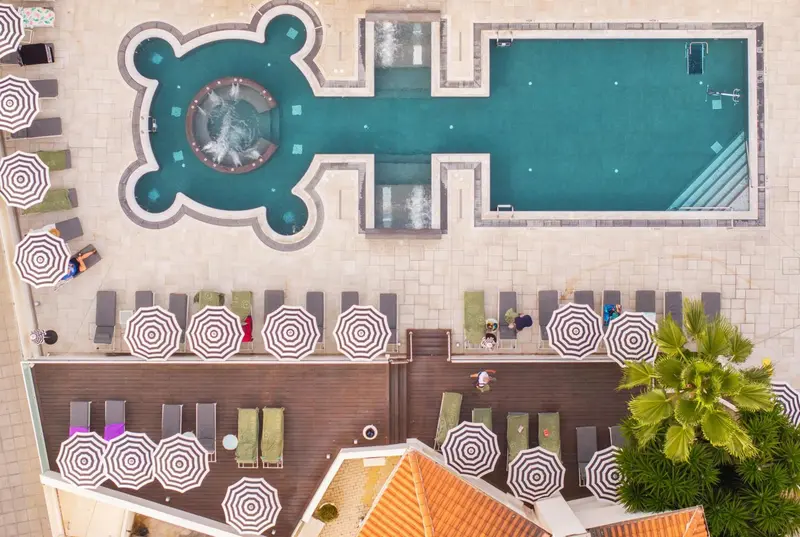 Vue aérienne d'une piscine en forme de clé et de transats disposés autour.