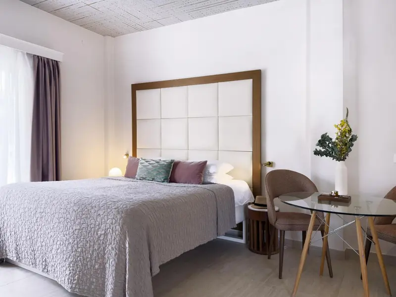 Une chambre lumineuse avec un grand lit et une petite table.