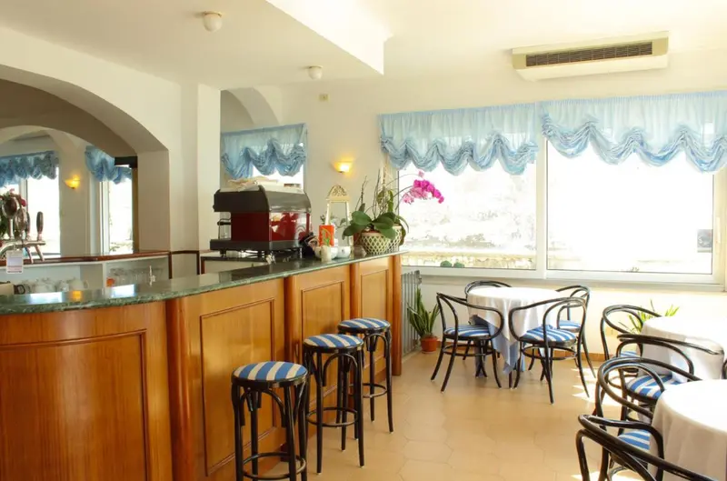 Un bar lumineux avec des tabourets et des tables à proximité d'une fenêtre.