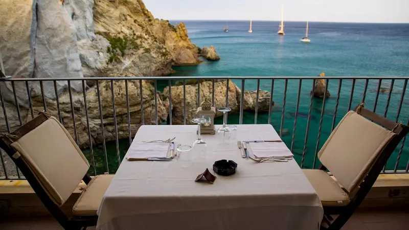 Table dressée sur une terrasse avec vue sur la mer et les falaises.