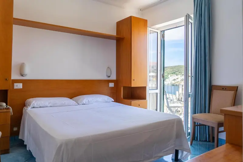 Une chambre lumineuse avec un lit double et un accès à un balcon.