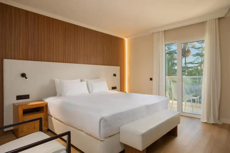 Une chambre lumineuse avec un grand lit et un accès à une terrasse.