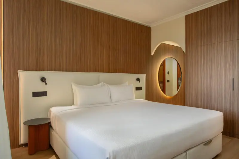 Une chambre lumineuse avec un grand lit et un miroir rond.